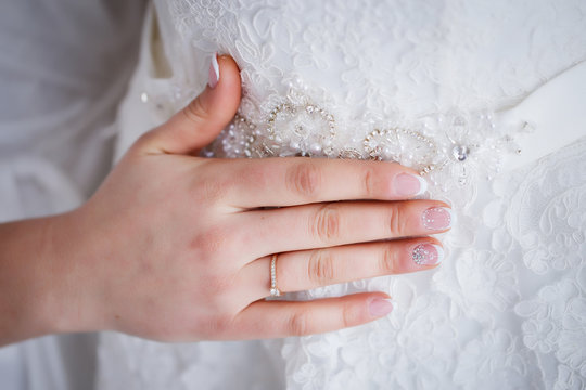 A girl with a beautiful manicure touches a wedding dress