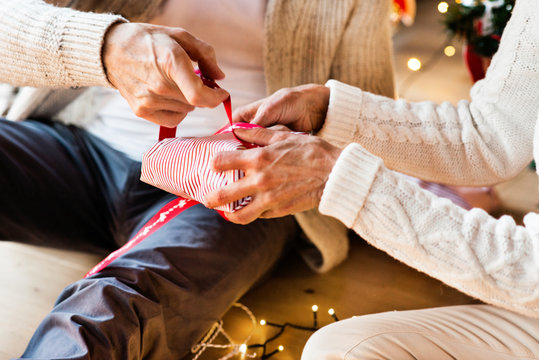 Unrecognizable senior couple wrapping Christmas gifts together.