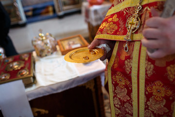 priest holding a gold wedding ring for wedding couple