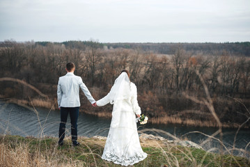 Fototapeta na wymiar loving couple walking by the river on their wedding day