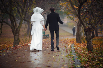 loving couple walking in autumn park in rainy weather