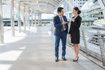 Asian businessman and businesswoman surf internet and chat with friend on mobile phone. with copy space for text