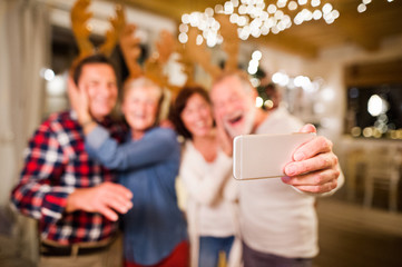 Senior friends with smartphone taking selfie at Christmas time.