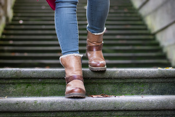 Girl wearing stylish fall leather boots. Woman feet walking down the stairs. 