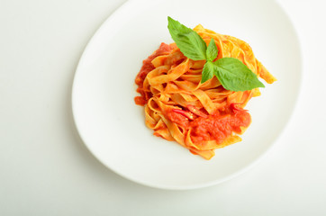 Pasta in tomato sauce  decorated basil on a plate isolated on white background