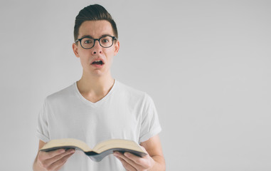 nerd with glasses and a white t-shirt is reading a book on a white background
