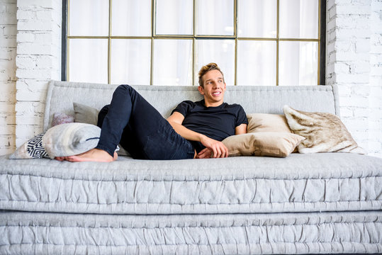 A Young Handsome Man Relaxing On The Sofa In A Loft Style Apartm