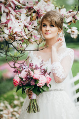 Amazing blonde bride near magnolia tree