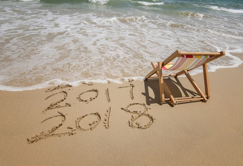 Fototapeta premium Deck chair with 2018 and 2017 inscription written in sand write on tropical beach.