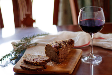 bread and a glass of wine on a wooden board and table