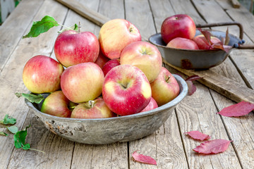 An old bowl of apples on a wooden table
