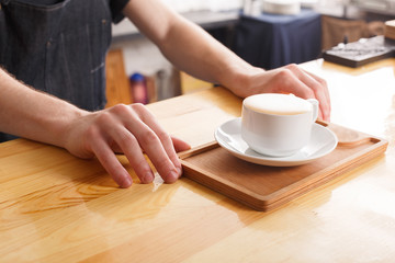 Barman serving coffee cup on wooden bar counter