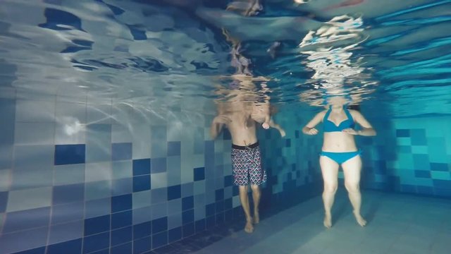 The family is swimming in the pool. Joint diving under water. Swimming under water. A successful attempt.