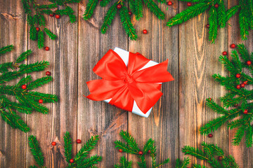 Spruce branches with red berries on a wooden table. In the center of the box with presents are bandaged bows. Christmas, holiday.