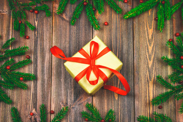 Spruce branches with red berries on a wooden table. In the center of the box with presents are bandaged bows. Christmas, holiday.