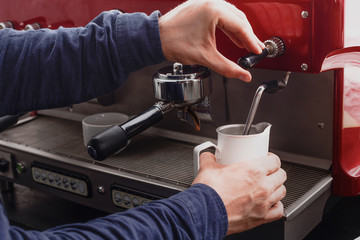 Closeup of barmen hand steaming milk in professional coffee machine