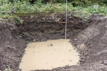 Excavation pit with groundwater ingress and measuring bar