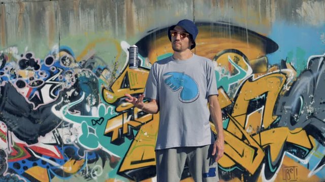 A front view on a graffiti artist juggling a paint can. 