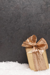 Christmas greeting card. Noel festive background. New year symbol. Gold gift box on snow. Festive background with copy space.