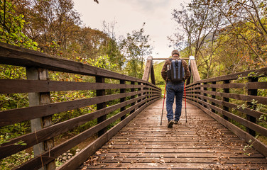 hike man with backpack walking in forest nature outdors bridge.