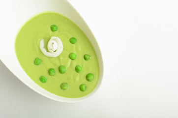 Green peas cream soup in a bowl isolated on white background