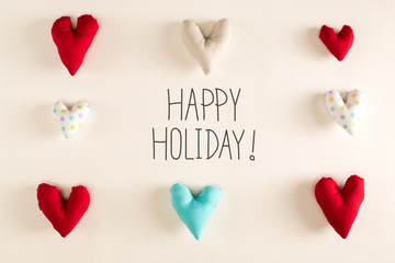 Happy Holiday message with blue heart cushions on a white paper background