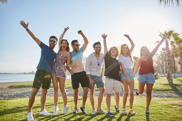 Group of friends raising hands together outside laughing