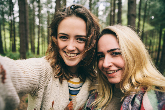 Two teenage girls taking selfie in woodland