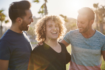 Three happy male friends laughing together outside