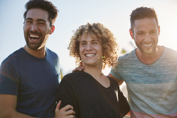 Three handsome male friends laughing together outside