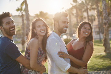 Two happy couples standing together outside looking away