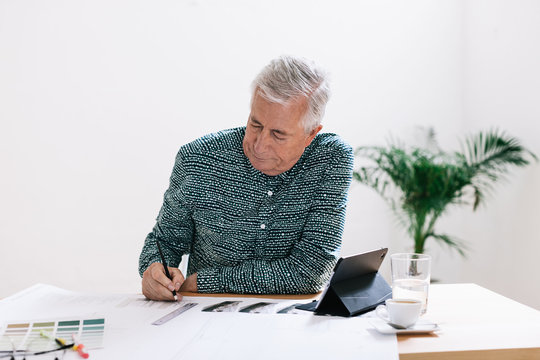 Elderly creative businessman working at desk.