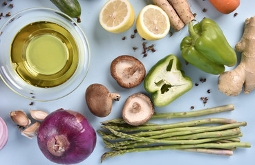 Collection of fresh vegetables and bowl of olive oil on blue background. Top view.