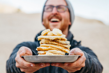 young male holding stack of pancakes while laughing