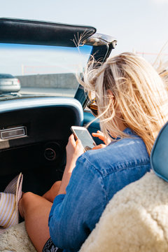 young female on mobile cell phone while riding in convertible car