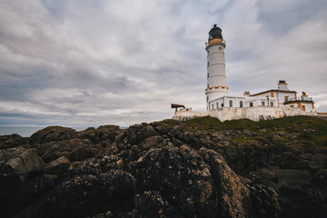 Fototapeta na wymiar Old lighthouse on the rock coast of sea