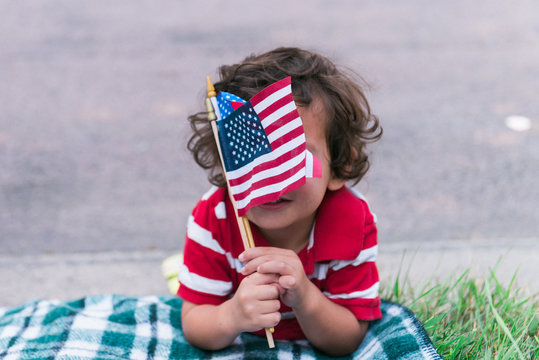 little boy at a parade waving an American flag