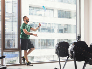 Man in a gym throwing a bottle up in the air.