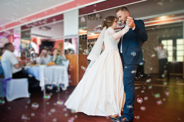 Beautiful wedding couple performing their first dance in the restaurant with different lights and...