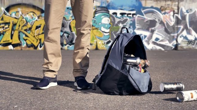 A man opens his hand with a backpack full of spray paints. 