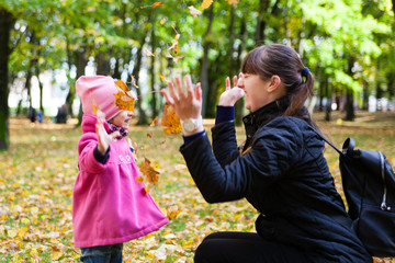 Fototapeta premium happy family mother and girl child little daughter play cuddling on autumn walk in nature outdoors in the park with fall leaves