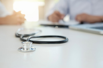 Patient listening intently to a male doctor explaining patient symptoms or asking a question as they discuss paperwork together in a consultation