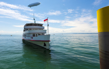 Excursion boat comes to landing stage  of Hagnau, zeppelin in the background - Hagnau, Lake Constance, Baden-Wuerttemberg, Germany, Europe © karlo54
