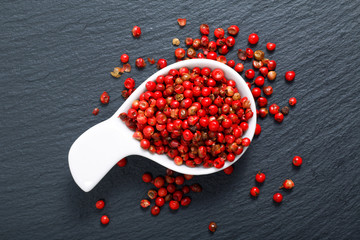  Organic Pink Peppercorn in white ceramic cup on black slate stone background