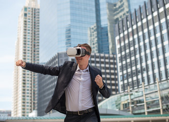Caucasian Businessman wearing black suit and Virtual Reality Headset (VR) and fighting by punch to...