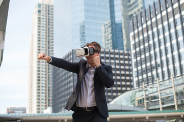 Caucasian Businessman wear black suit and Virtual Reality Headset (VR) and fighting by punch to the...