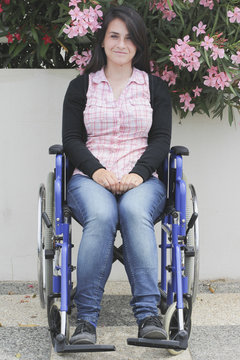 Young woman on a wheelchair against a wall full of flowers