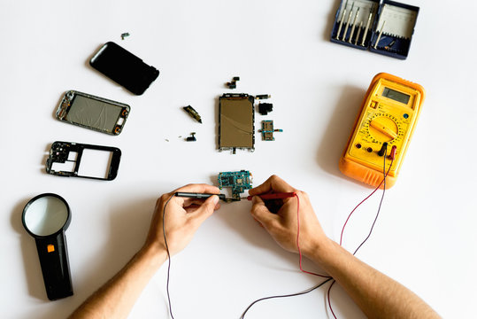 Man Using Multimeter On Broken Cell Phone