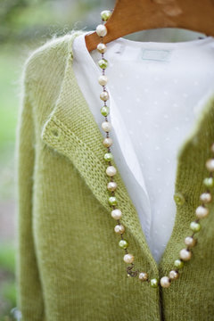 Ancient pearls necklace, cardigan and shirt on coat hanger