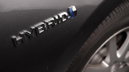 Focus is made on the Hybrid badge of a car.